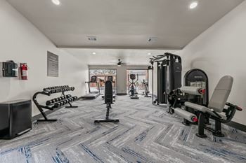 A gym with a variety of equipment including treadmills, weights, and exercise machines.